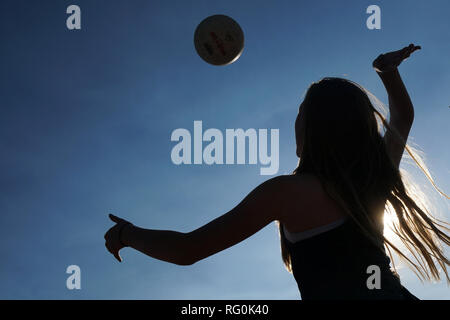 La silhouette d'une fille de frapper un terrain de volley-ball. Banque D'Images