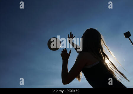 La silhouette d'une fille de frapper un terrain de volley-ball. Banque D'Images