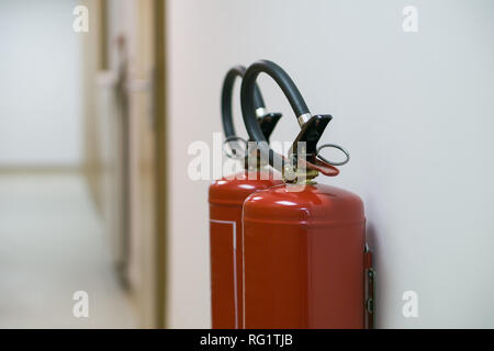 Extincteur rouge dans le corridor vide sur le mur blanc Banque D'Images