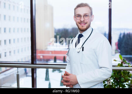 Sourire confiant médecin à la réception, le personnel médical travaillant sur l'arrière-plan Banque D'Images