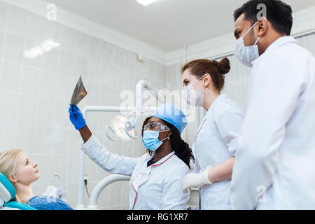 La santé et les soins de santé. Un groupe multinational de dentistes examine les rayons x en présence d'un patient. La pratique à une université médicale. Banque D'Images