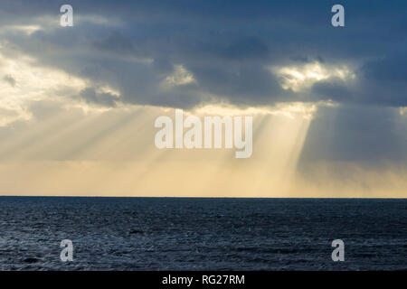 West Bay, Dorset, UK. 27 janvier 2019. Météo britannique. Poutres apparentes du soleil à travers les nuages au-dessus de la baie de l'Ouest dans le Dorset par une froide après-midi breezy Photo Credit : Graham Hunt/Alamy Live News Banque D'Images