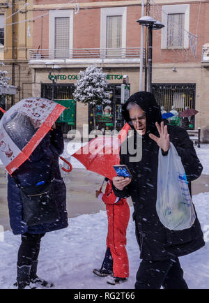 Homme marchant dans la rue pendant une tempête de neige, looking at smartphone, les gens derrière lui, des parasols, Avezzano, Abruzzes, Italie, Europe Banque D'Images