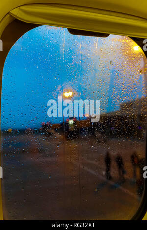 Gouttes de pluie sur la fenêtre de l'avion mis à la terre par la piste avec arrière-plan flou. Un soir de pluie sur l'aire de l'aéroport de flou artistique avec des gouttes de pluie tombant sur le Banque D'Images