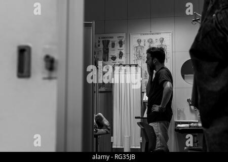 Un homme blanc italien, travaillant comme phisiotherapist est photographié alors qu'au travail tout au long de la dat dans un hôpital en Italie. Banque D'Images