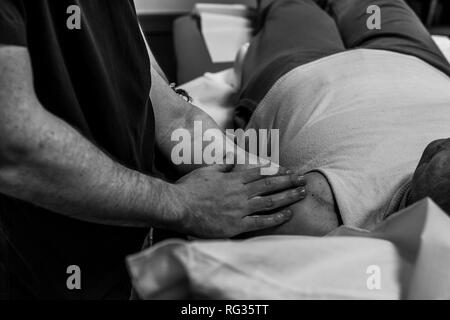 Un homme blanc italien, travaillant comme phisiotherapist est photographié alors qu'au travail tout au long de la dat dans un hôpital en Italie. Banque D'Images