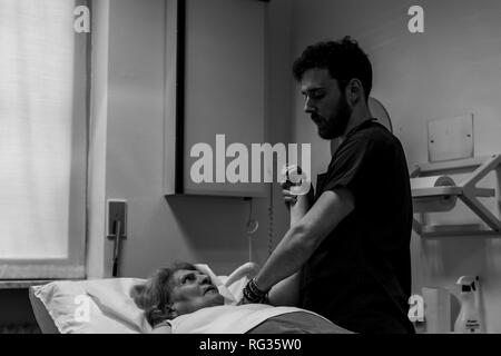 Le physiothérapeute Riccardo di Lauro travaillant sur une femme blanche qui présente une cicatrice sur son épaule gauche, qui est allongé sur un lit d'hôpital dans le Banque D'Images