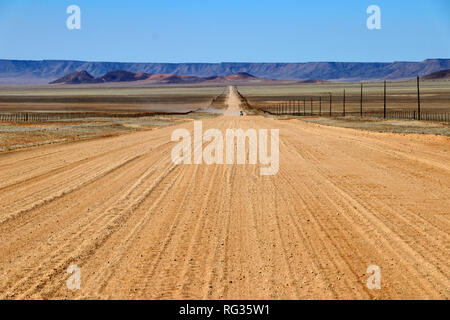 Longue route sans fin dans l'herbe de la steppe avec des montagnes de l'Afrique - Namibie Banque D'Images