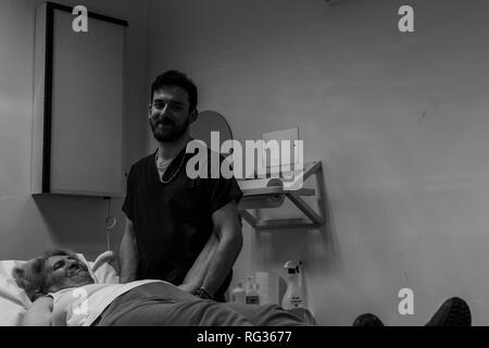 Un homme blanc italien, travaillant comme phisiotherapist est photographié alors qu'au travail tout au long de la dat dans un hôpital en Italie. Banque D'Images