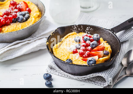 Dutch pancake aux fruits rouges pour bébé dans une casserole en fonte sur un fond blanc. Banque D'Images