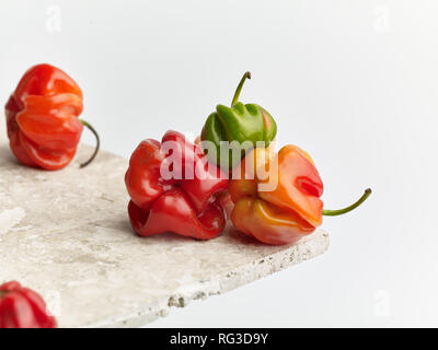 Poivre Scotch Bonnet tacheté et surface en marbre contre fond clair. Photographie alimentaire Banque D'Images