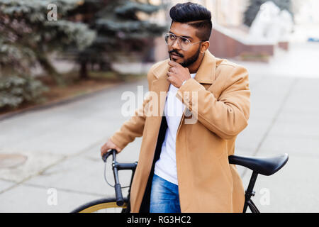 Portrait of Indian hipster barbu avec les cheveux bruns marcher avec fix location sur street Banque D'Images