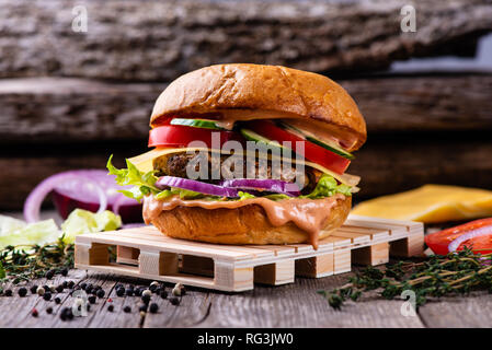 Hamburger frais sur table en bois vieilli, restauration rapide. Vintage table et fond, copy space Banque D'Images