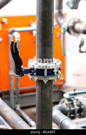 Tuyau en acier avec la touche Contrôle, orange table comme arrière-plan et d'autres tuyaux et des clés, l'environnement industriel Banque D'Images