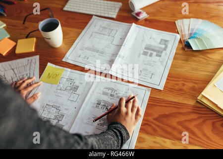 Cropped shot of female architect travailler avec plan d'étage d'une maison à l'office. Mains de femme interior designer working on new plan de bâtiment. Banque D'Images