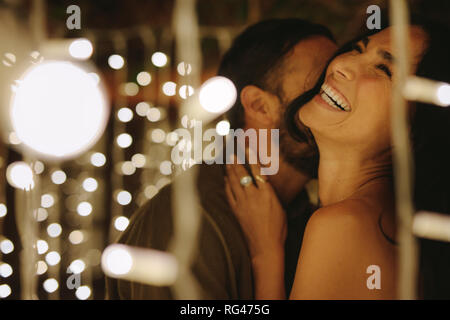 Happy young couple embracing avec des lumières autour du parti. Young man and woman embracing et rire. Banque D'Images