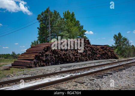 Un gros tas de traverses de chemin de fer inutilisées à côté de la pile de rails de chemin de fer. (La saturation élevée) Banque D'Images