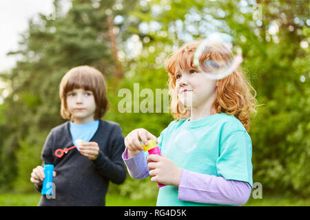 Deux jeunes filles faire des bulles de savon et de rêve sur une partie d'anniversaire pour enfants Banque D'Images