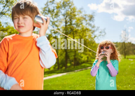 Deux enfants communiquent avec un téléphone filaire dans un parc Banque D'Images