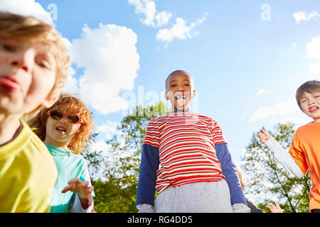 Les enfants dans l'école maternelle internationale autour de tromper effrontément et montrer leur langue maternelle Banque D'Images