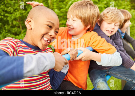 Les enfants dans la maternelle joyeuse multiculturelle jouent sur un mur d'escalade Banque D'Images