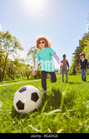 Les enfants jouent au football au camp d'été sur un pré à l'été pratiques le tir au but Banque D'Images