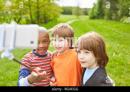 Trois enfants en amis prendre un avec leur smartphone selfies sur le Stick Selfies Banque D'Images