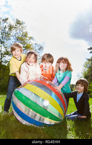 Groupe multiculturel d'enfants joue avec une balle dans le jardin d'enfants international Banque D'Images