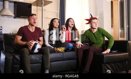 Quatre jeunes amis assis sur le canapé et regarder match de football portant des attributs russe Banque D'Images