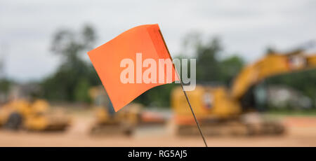 Un bokeh rapprochée sur un drapeau d'avertissement sur un site de construction de l'équipement avec des machines lourdes à l'arrière-plan. Banque D'Images