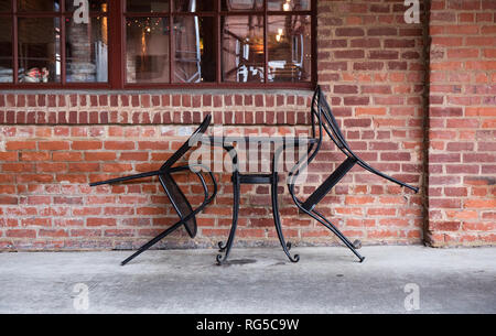 Une table pour deux dans un café en plein air en milieu urbain avec les chaises en fer appuyé contre la table. Banque D'Images