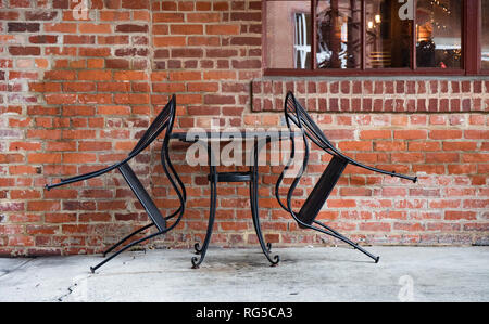 Une table pour deux dans un café en plein air en milieu urbain avec les chaises en fer appuyé contre la table. Banque D'Images