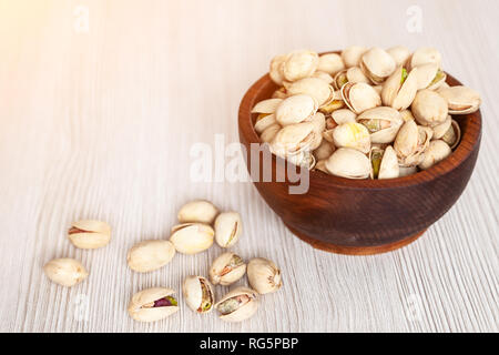 Pistaches pelées dans un pin de cèdre sur une plaque de fond en bois isolé. Rangée de boules avec les pistaches. Pistaches pelées pattern Banque D'Images