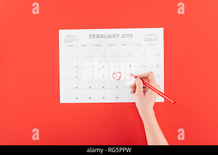 Portrait de femme tenant un marqueur au-dessus calendrier avec 14 février date marquait isolé sur rouge, st valentines day concept Banque D'Images