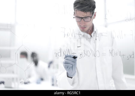 Scientifique sérieux écrit une formule chimique sur un verre. Banque D'Images