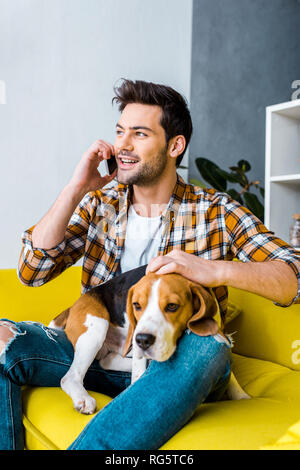 Handsome cheerful man talking on smartphone et un chien beagle Banque D'Images