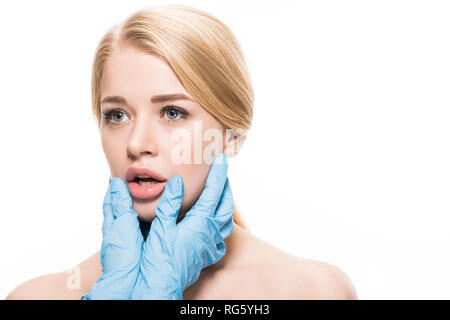 Cropped shot of cosmetologist gants en latex de toucher le visage et les lèvres de la jeune femme isolated on white Banque D'Images