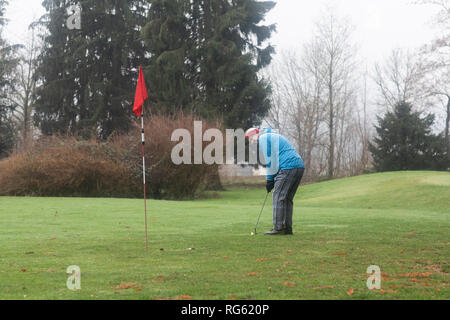 L'homme de mettre une balle de golf sur un parcours de golf en hiver, Allemagne Banque D'Images