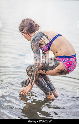 Girl standing in Atanasovsko Lake couvrant elle-même dans la boue, Burgas, Bulgarie Banque D'Images