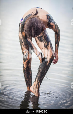 Girl standing in Atanasovsko Lake couvrant elle-même dans la boue, Burgas, Bulgarie Banque D'Images