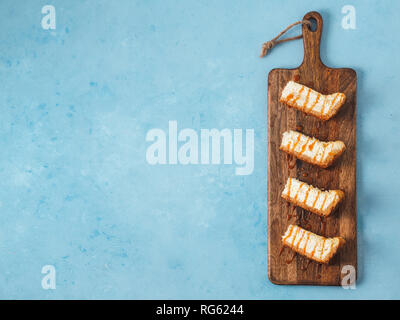 Tranches de gâteau caramélisé sur bois cuttingboard. Gâteau au fromage sur fond bleu avec copie espace pour le texte. Vue de dessus ou de télévision. Banque D'Images