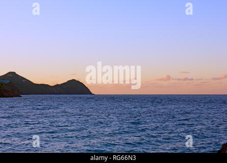 Coucher de soleil sur la mer des Caraïbes avec les Samoa américaines sur l'horizon. Soleil se couche derrière un paysage montagneux de l'île de Saint Thomas. Banque D'Images