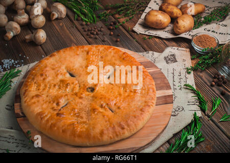 Les pommes de terre et champignons tarte sur une table de cuisine en bois avec des ingrédients. Concept de cuisson fait maison. Menu livraison with copy space Banque D'Images