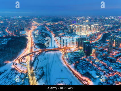 Vue aérienne de la belle ville moderne à la nuit froide en hiver. Vue de dessus de la circulation sur les routes, les bâtiments, les rues enneigées avec éclairage. Ligne d'horizon. Capitales Banque D'Images
