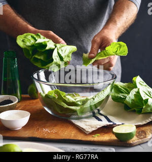 Mode de vie sain. Man Cooking Salade verte de laitue romaine. Concept d'aliments sains Banque D'Images