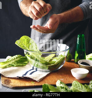 Mode de vie sain. Man Cooking Salade verte de laitue romaine. Concept d'aliments sains Banque D'Images