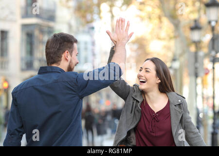 Deux excités amis ou couple giving high five in a city street Banque D'Images