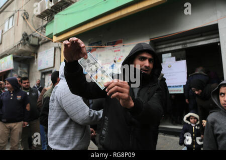 Un Palestinien vu la tenue d'un hundred dollar bill (100) après avoir reçu l'aide du Qatar à l'office de poste dans la bande de Gaza. Palestiniens, première phase du fonds d'aide du pays au bureau de poste et le fonds d'aide du Qatar ont été livrés à 44 000 familles dans la bande de Gaza. Banque D'Images