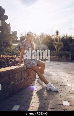 Attractive young woman wearing leopard print dress dans jardin public Banque D'Images