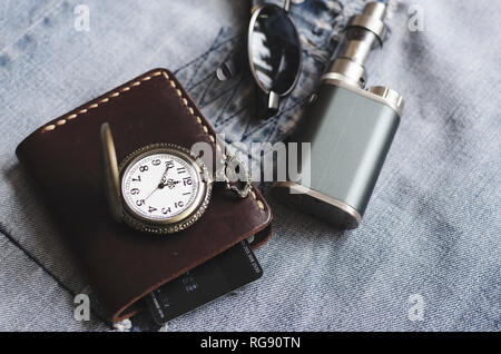 Accessoires Homme, montre, porte-monnaie, e cigarette et lunettes sur les blue-jeans Banque D'Images